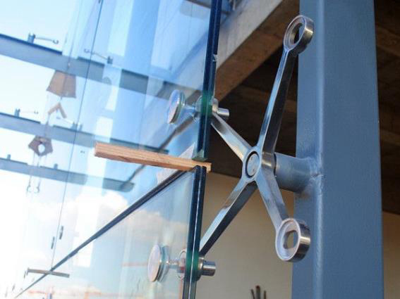 Detail view of stainless steel spider claw used to support the structure of a large glass wall.